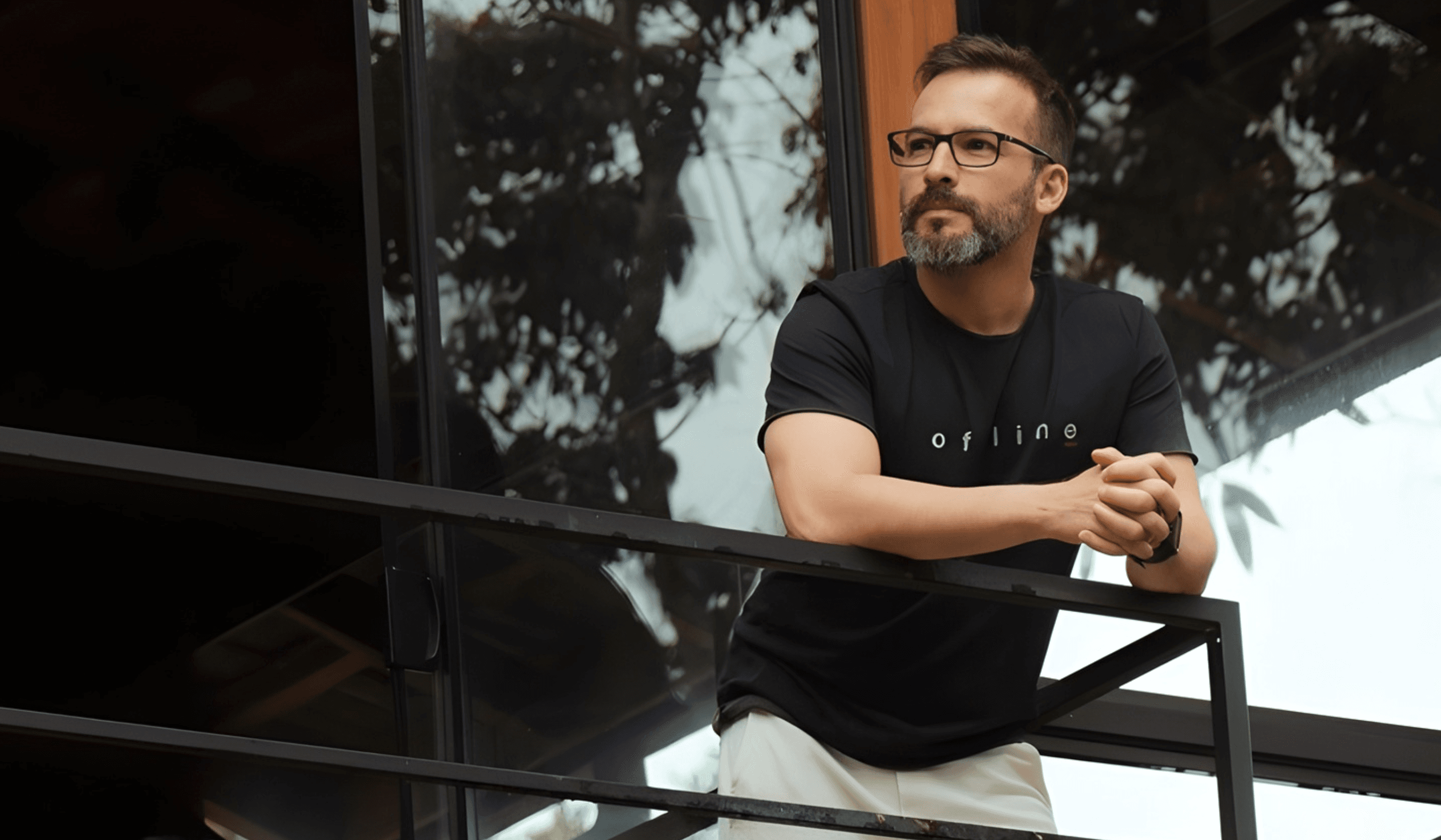 Valentim Magalhães apoiado em um guarda-corpo, vestindo camiseta preta